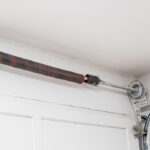 Close-up of a broken garage door spring showing coil damage and tension failure in overhead torsion system.