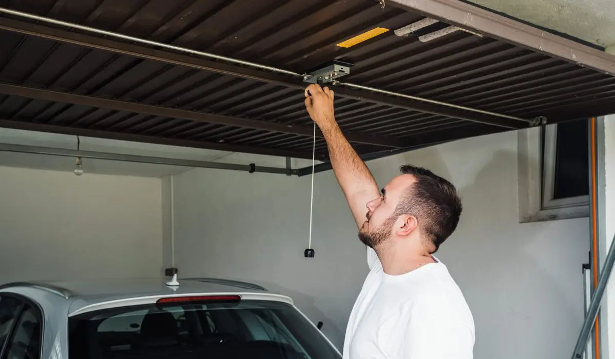 Man inspecting opener system as garage door makes noise during use.