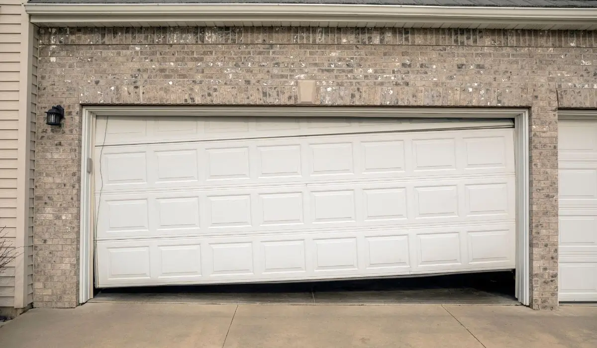 Garage door hanging unevenly due to failed garage door cable, showing the risk of delayed repair.
