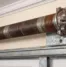Rust forming on residential garage door spring above entry showing corrosion and tension wear warning signs.