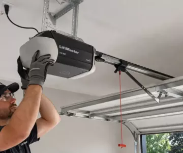 Garage door technician installing a LiftMaster opener system during a repair or replace garage door service inside a residential garage.