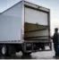 Fleet technician inspects box truck doors on a cold morning before vehicles begin scheduled winter delivery routes.