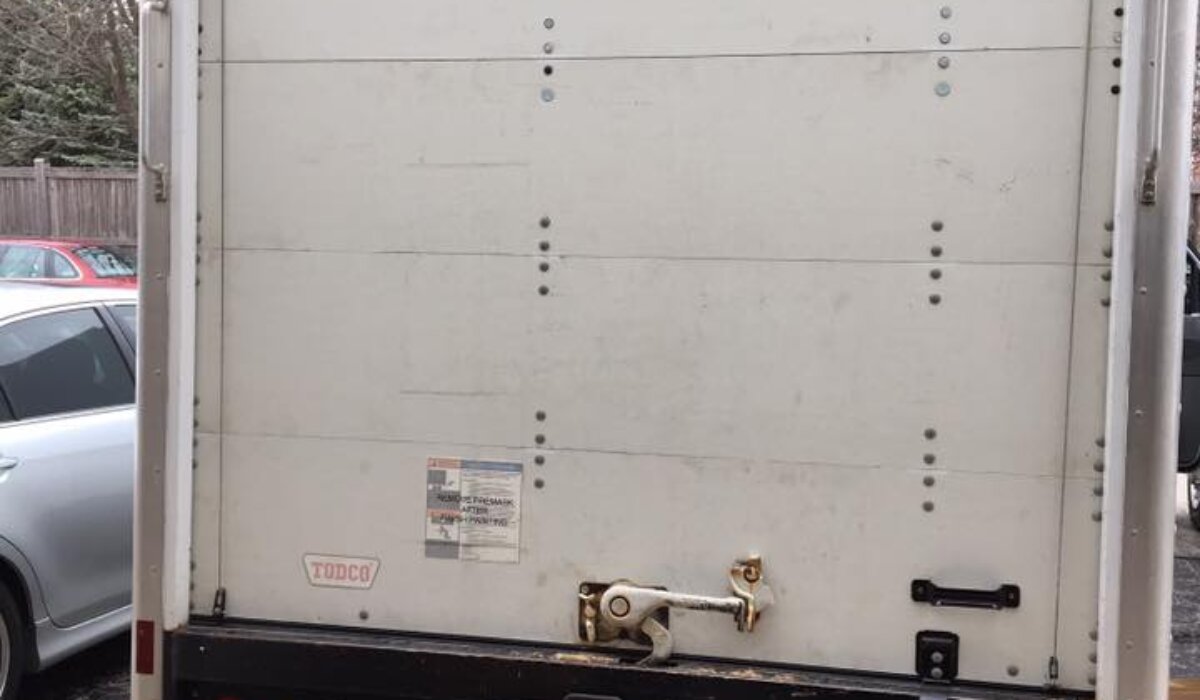Rear view of a white box truck needing maintenance, illustrating common issues requiring box truck roll-up door repairs.