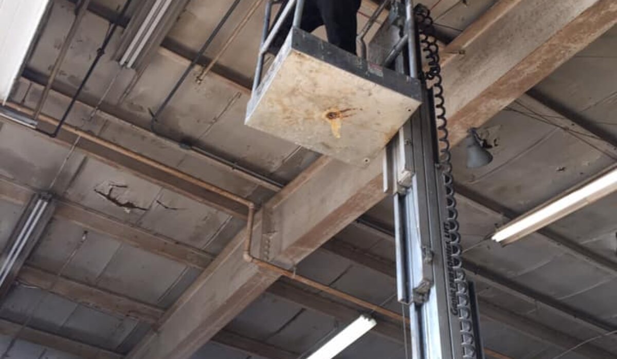 Technician performing commercial garage door inspection on an overhead door system inside an industrial facility.